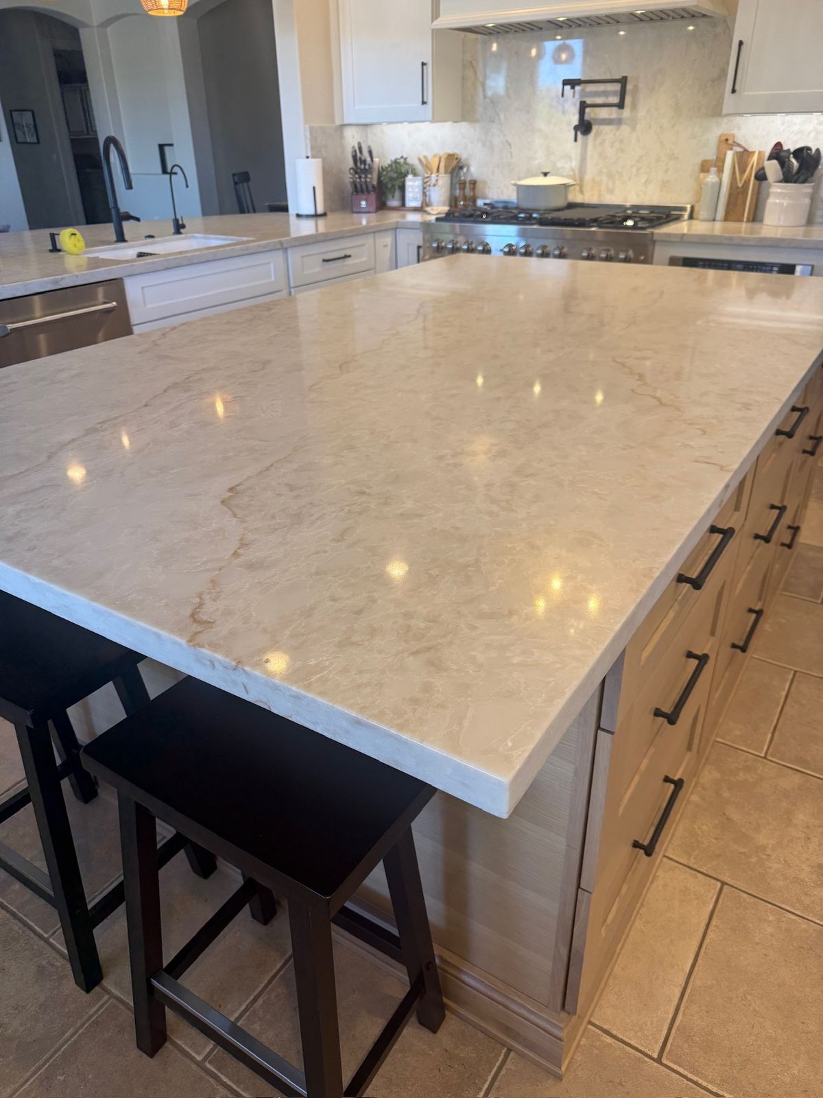 Stanley Brothers project: a large stone island with counter stools, the range wall behind it