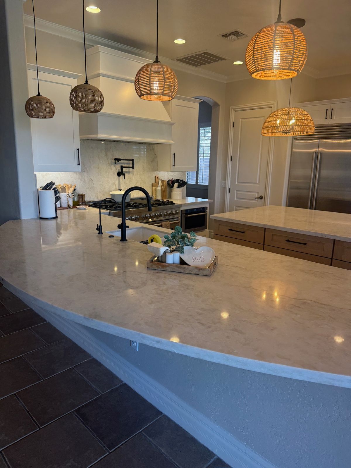 Stanley Brothers project: a curved stone island edge with the kitchen run and pendants behind